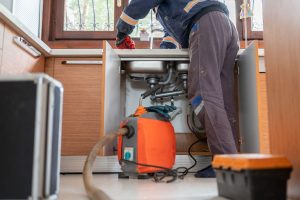 Benjamin Franklin Plumber unclogging a kitchen sink drain with professional equipment.