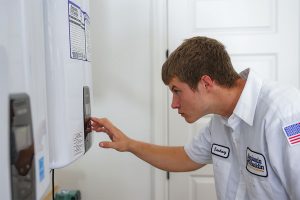 Benjamin Franklin Technician adjusting a tankless water heater in a residential home.
