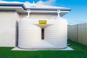 An outdoor rainwater storage tank connected to a house's gutter system