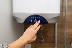 A Duncanville Plumber adjusting temperature on a wall-mounted water heater.